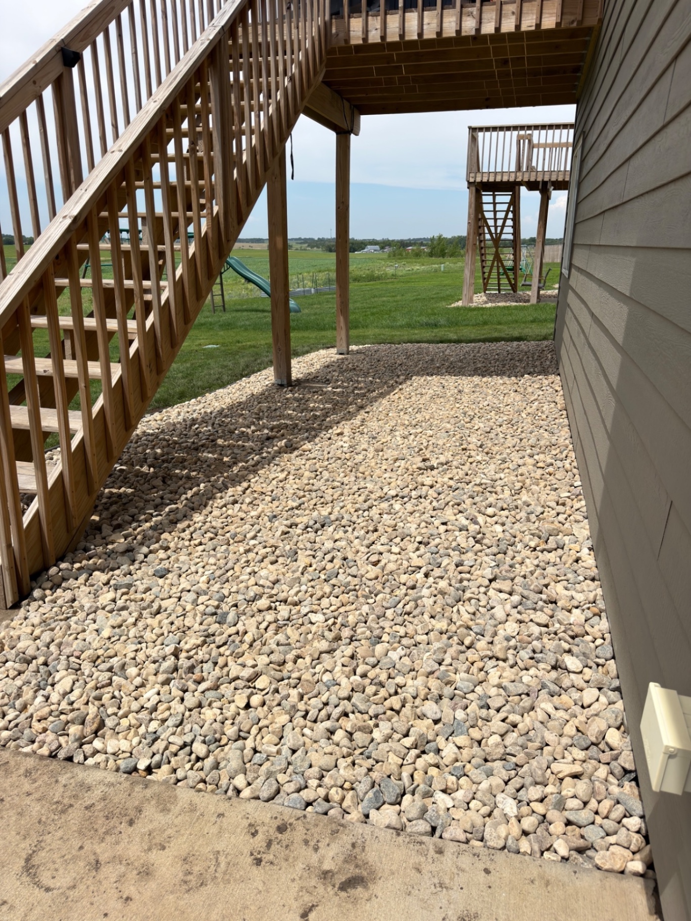 After — finished rock landscaping running under the deck stairs and along the side of the house to the back yard