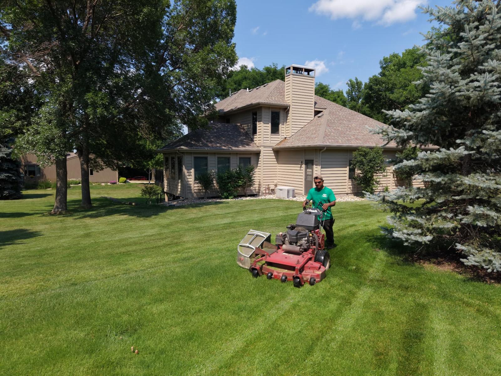 Drone view of a weekly mowing visit on a manicured Sioux Falls estate lawn with mature trees