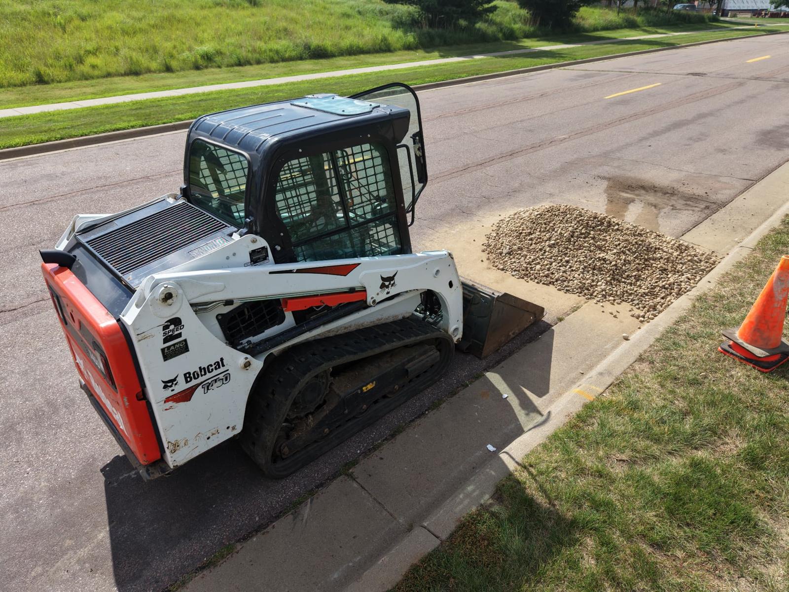 KPM Bobcat T450 compact track loader placing river rock during commercial site prep in Sioux Falls, SD