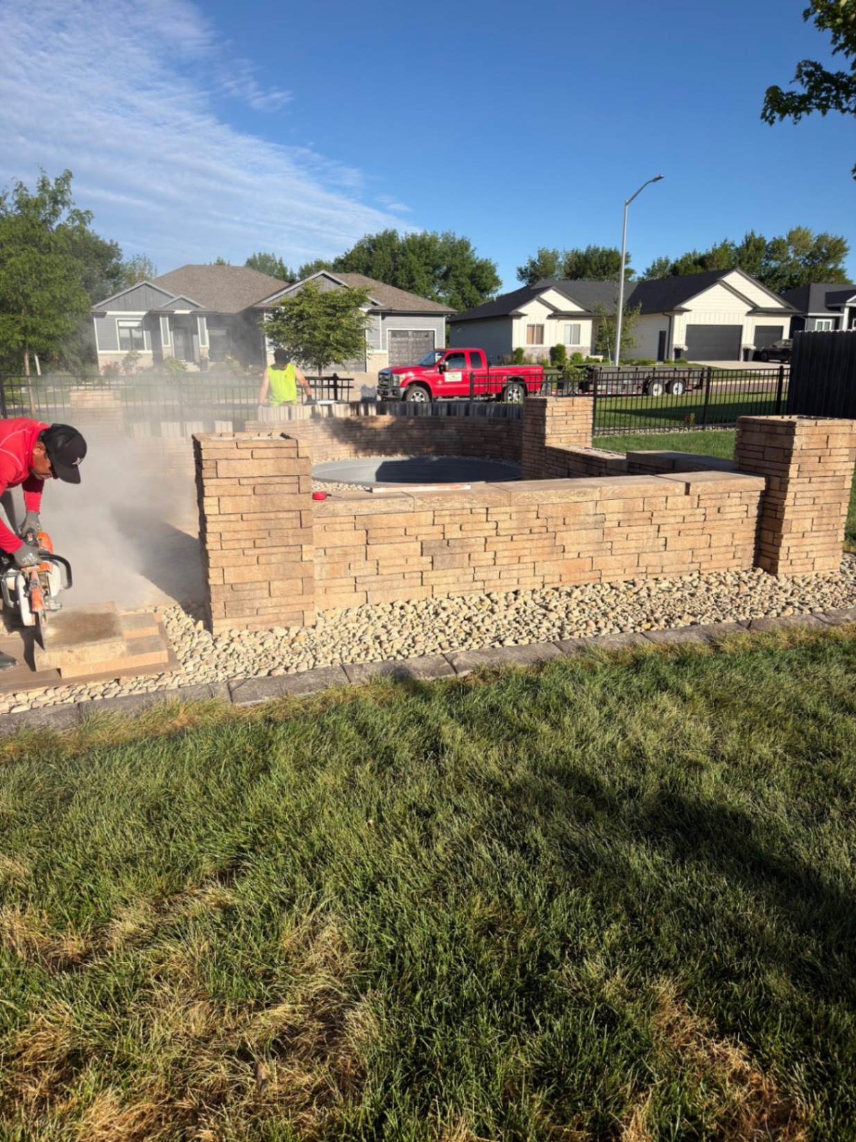 During — saw-cutting and finishing the seat wall near completion with river rock spread along the edge