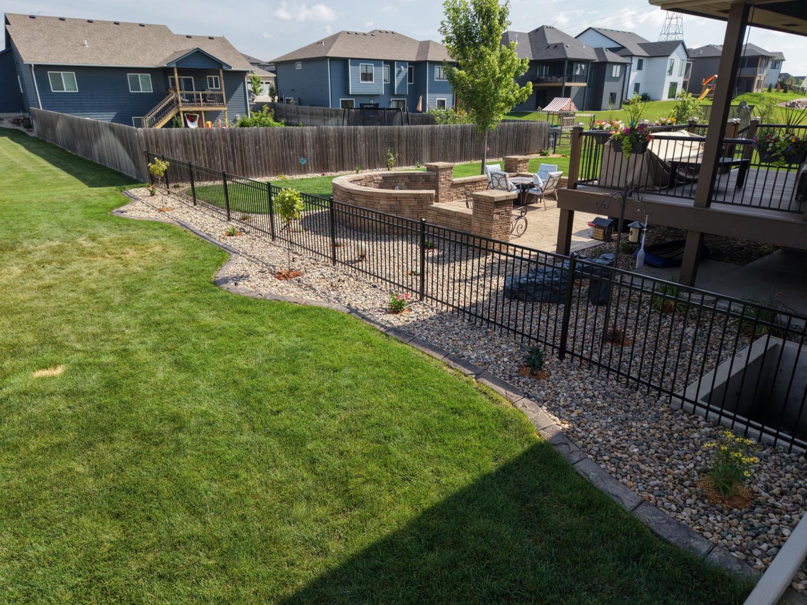 Stamped patio and fire pit seat wall along an iron fence in Sioux Falls, SD