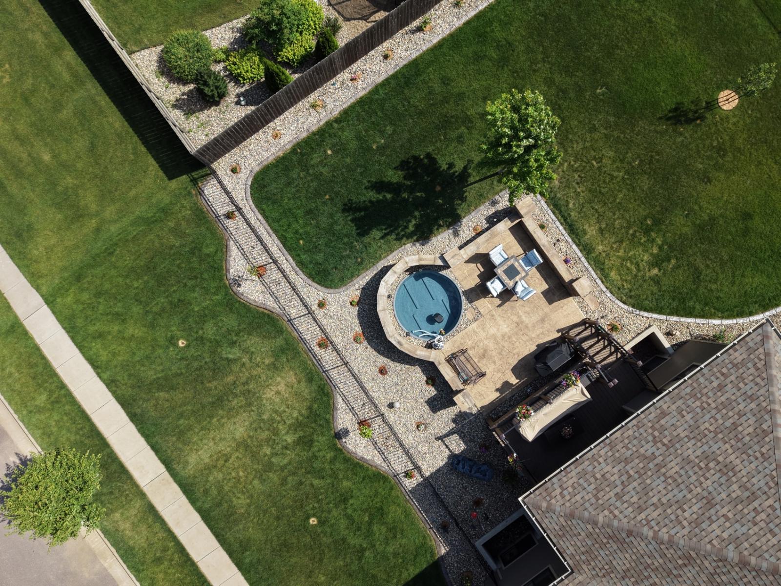 After — top-down aerial of full backyard design showing patio, stock tank pool, walkway, and rock bed layout