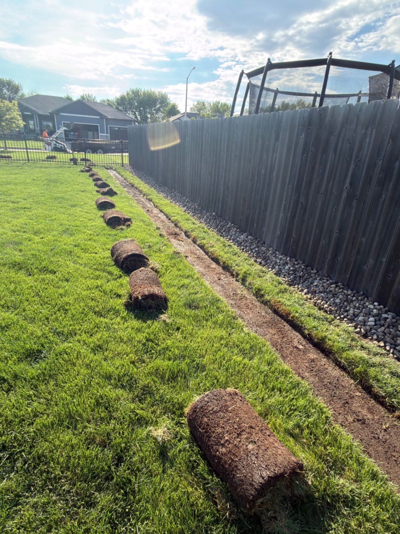 During — sod rolls pulled along the fence line as we cut out the new bed for the river rock border
