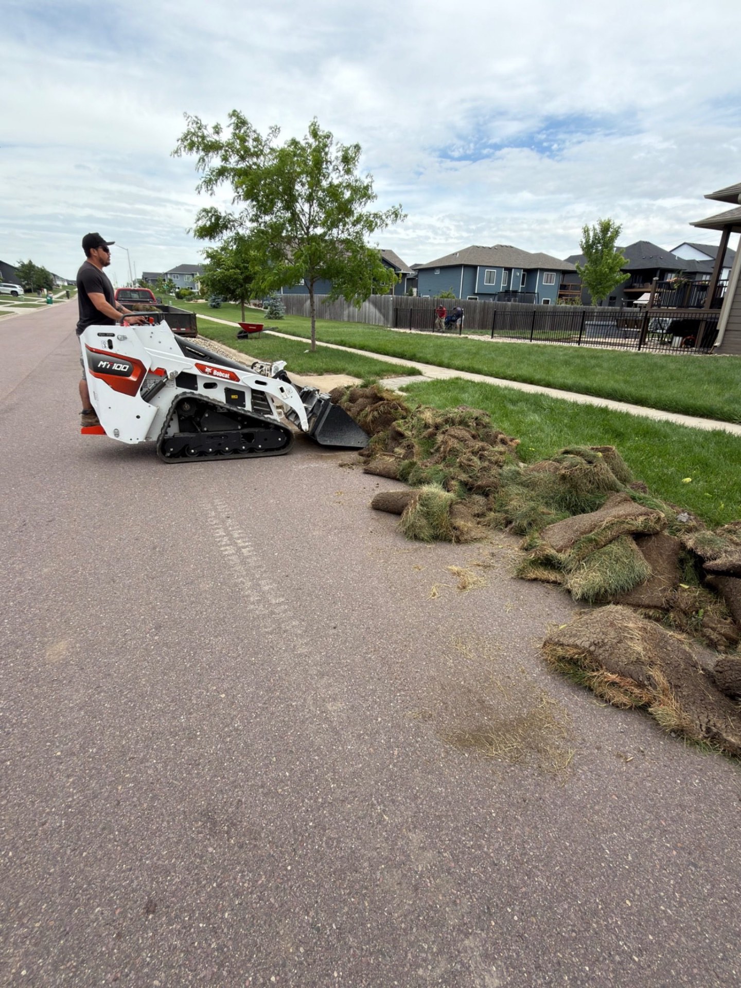 During — mini skid steer hauling out old sod to make room for the expanded rock beds and edging