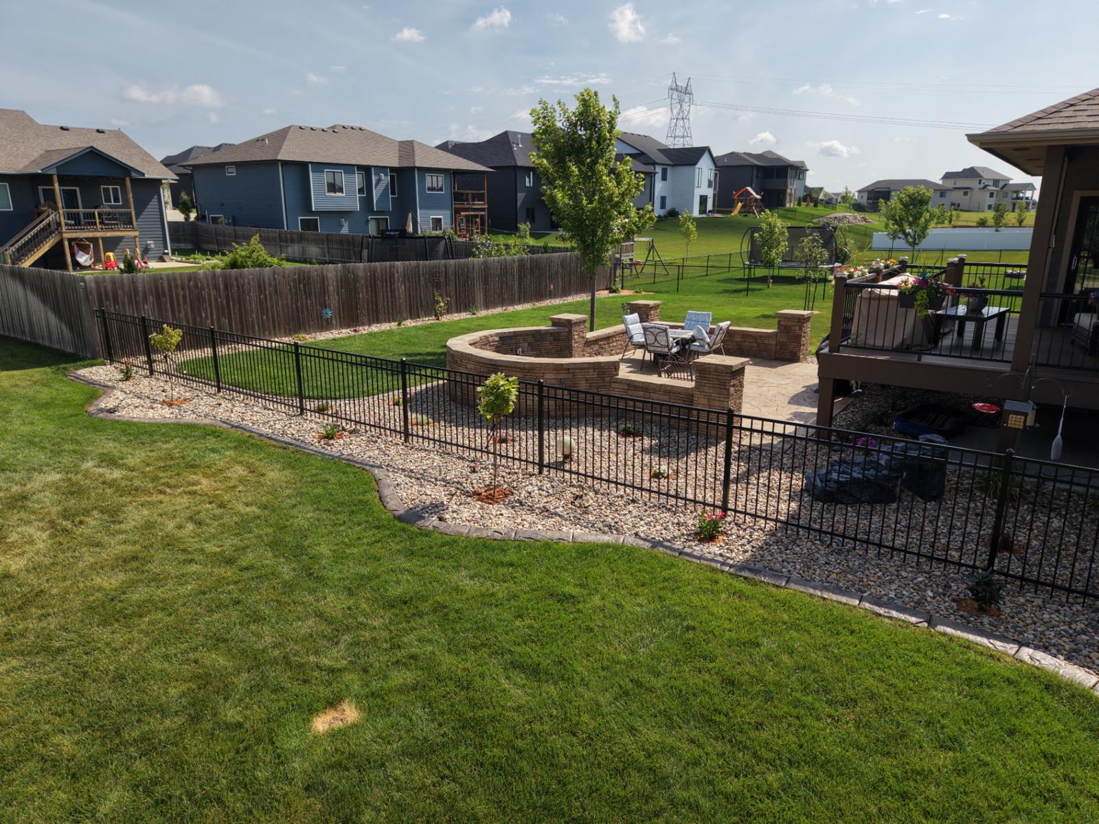 Wide backyard view of a stamped patio and fire pit seat wall built by Kerwin