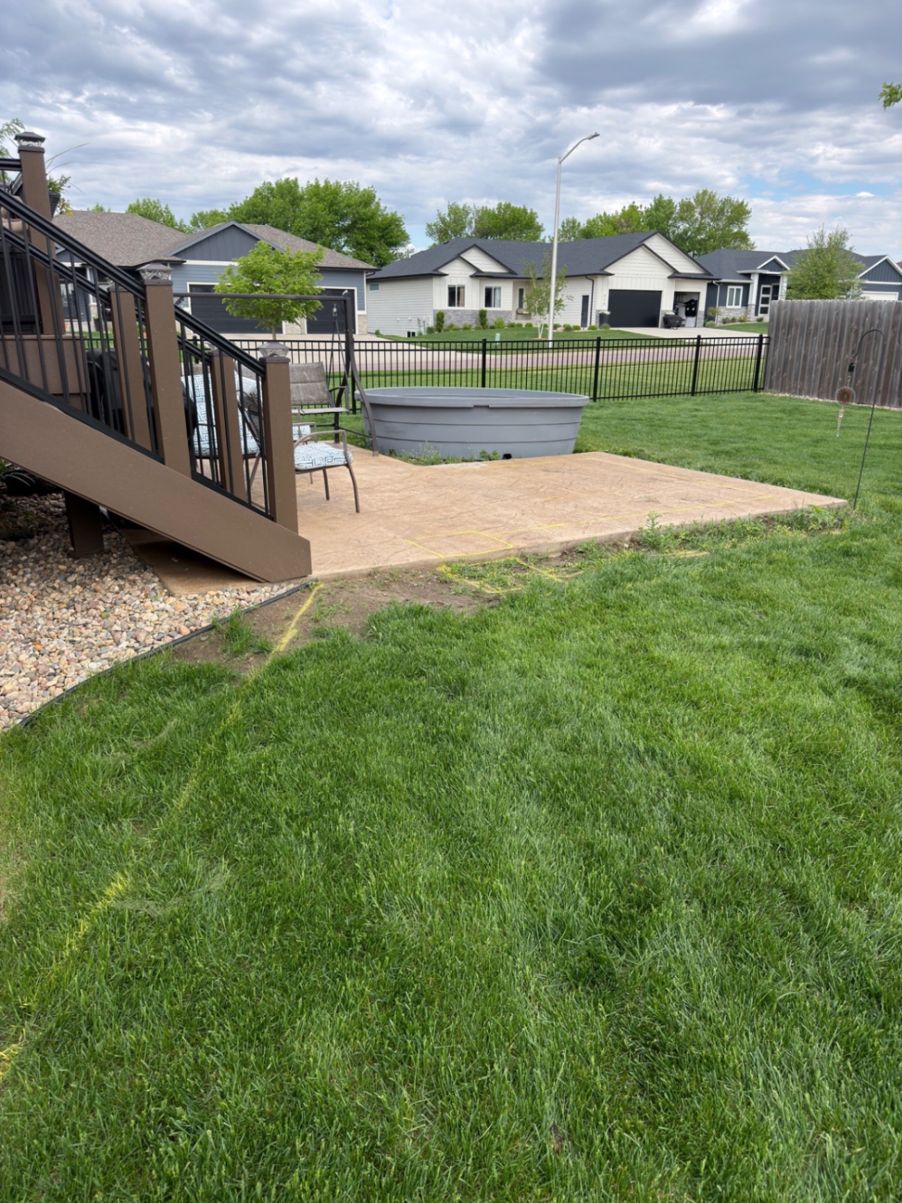 Before — original small stamped concrete pad with stock tank set up on the grass before the seat wall build