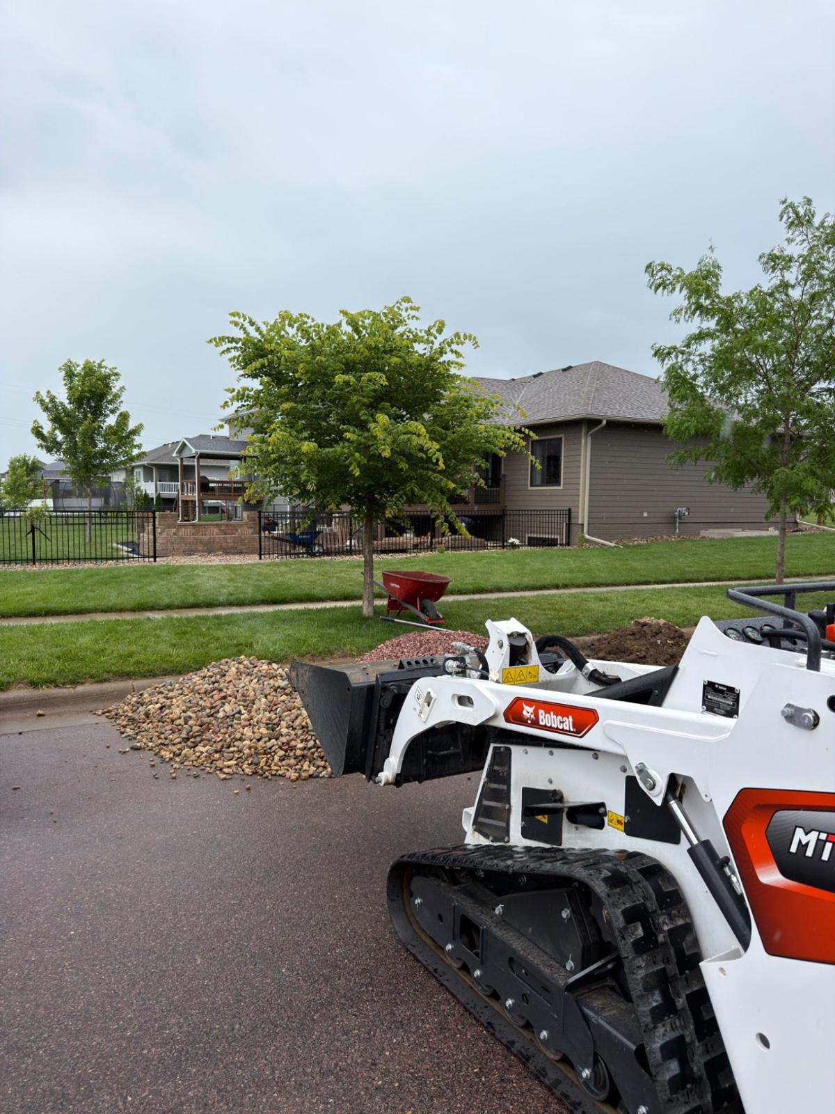 During — mini skid steer and river rock on site as materials are brought in for the surrounding landscape finish work