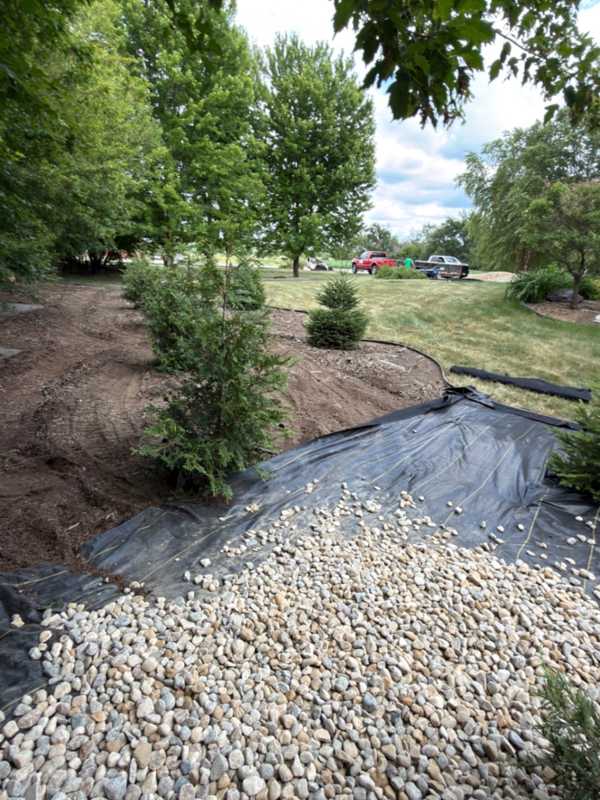 During — weed barrier laid down with fresh river rock starting to be spread along the edged bed line