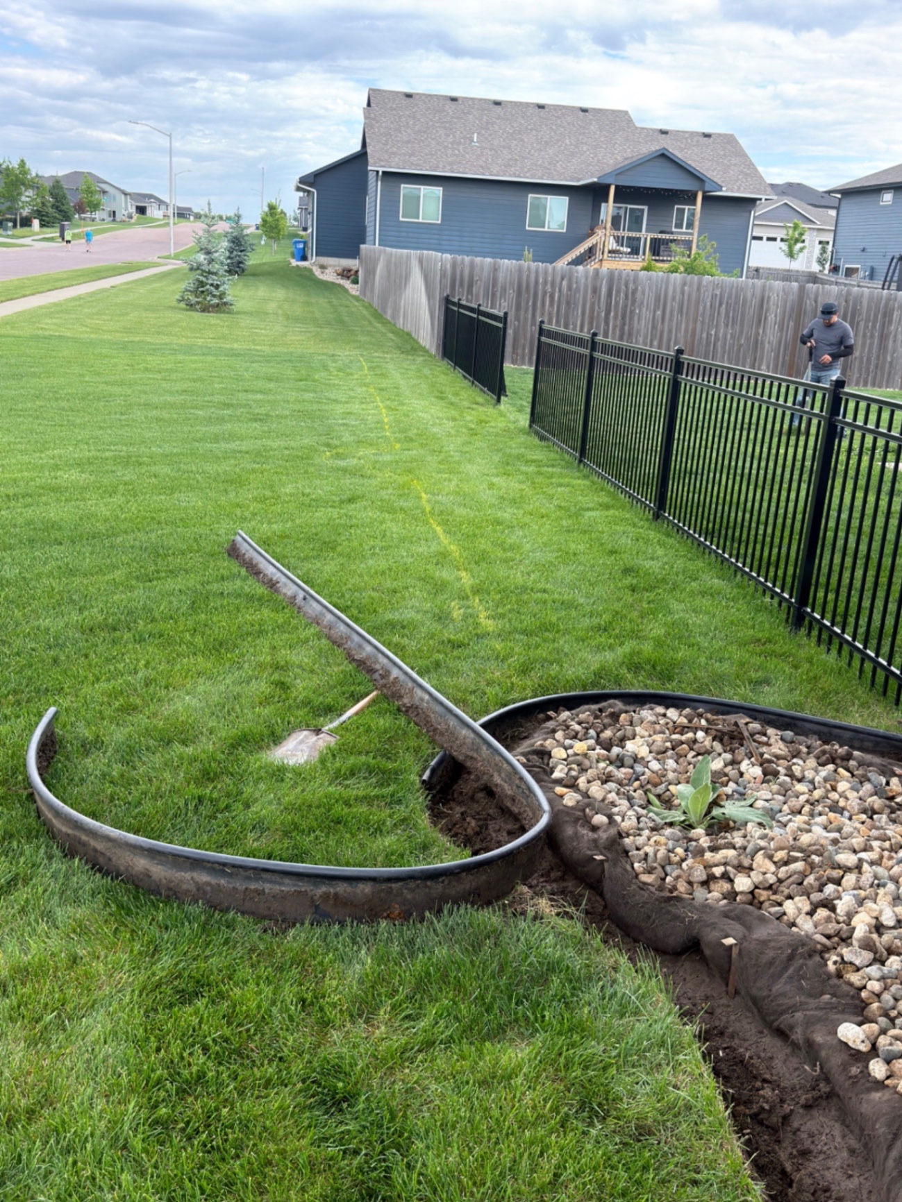 Before — existing rock bed and edging along the side yard before the custom seat wall and landscape redesign