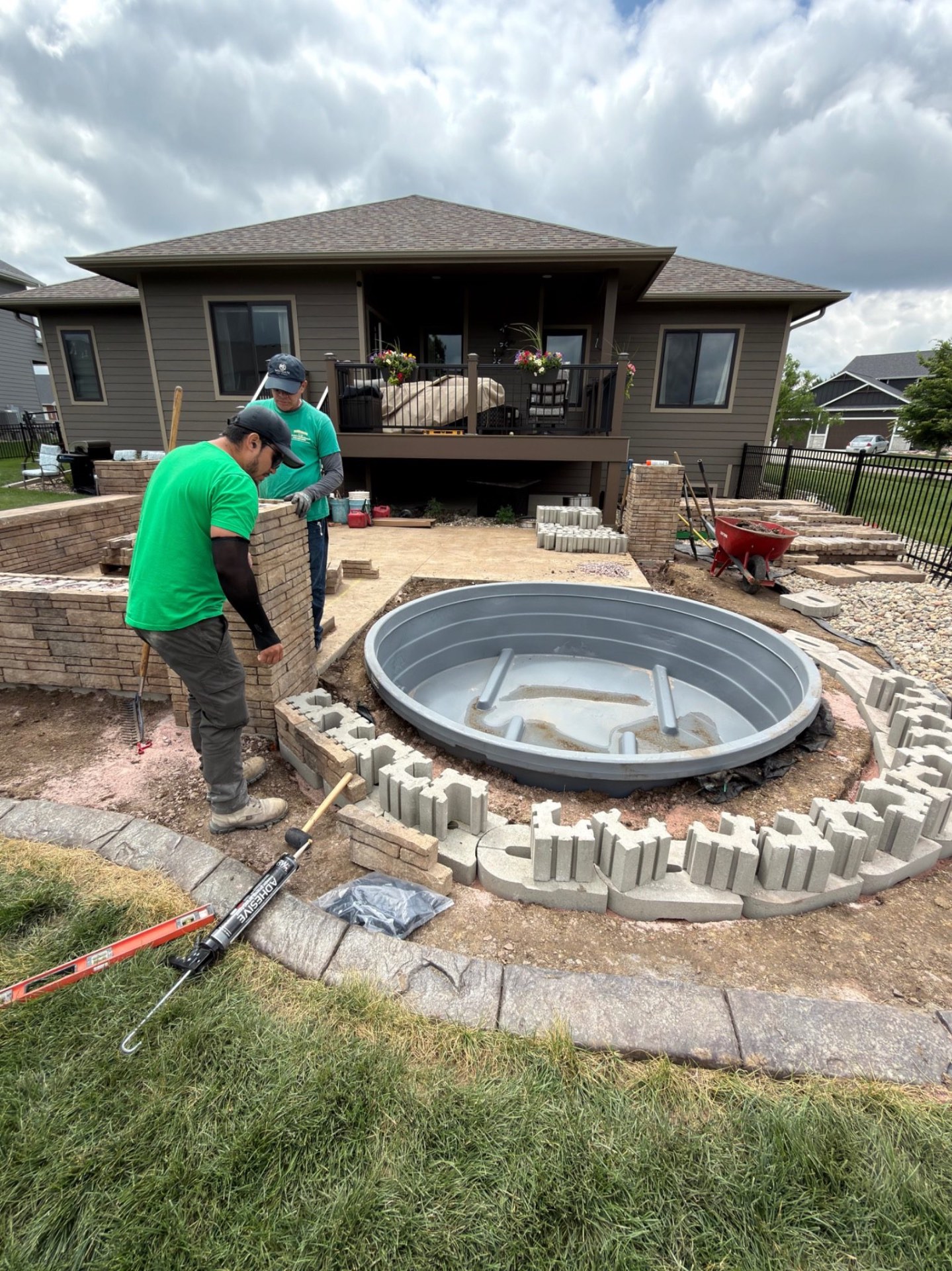 During — curved seat wall taking shape tightly around the stock tank pool with cap blocks and base pieces being fitted