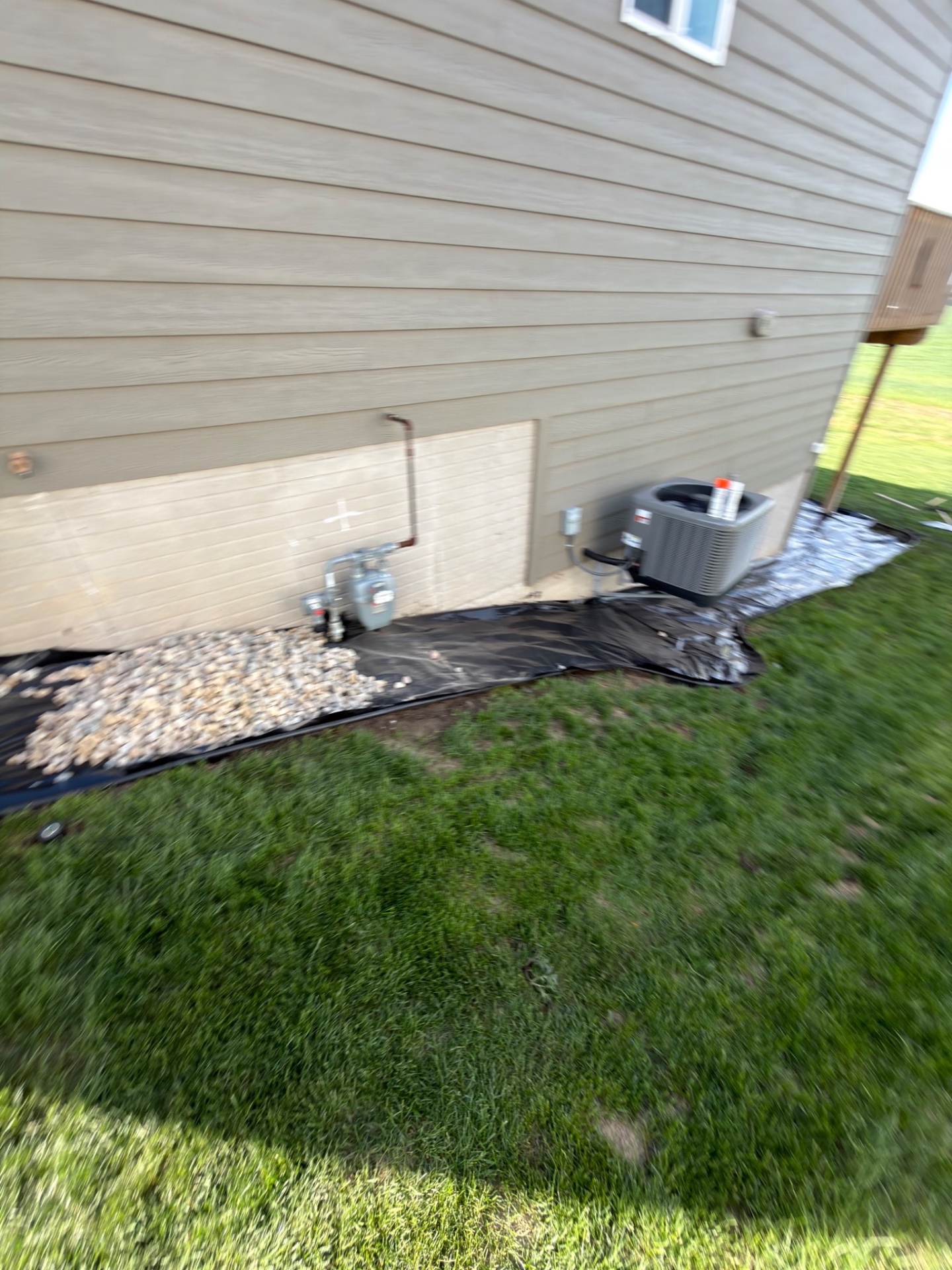 During — back side of the house with Edging rolled out around the AC unit and gas meter before rock is spread
