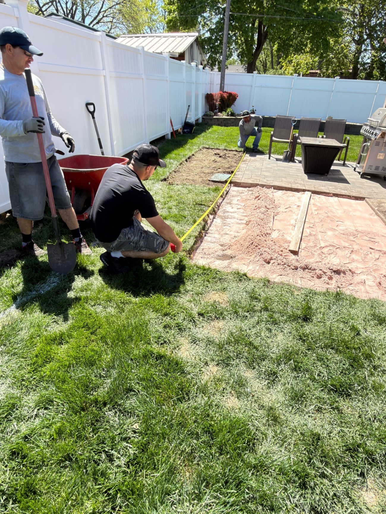 Before — crew measuring and prepping the patio extension area