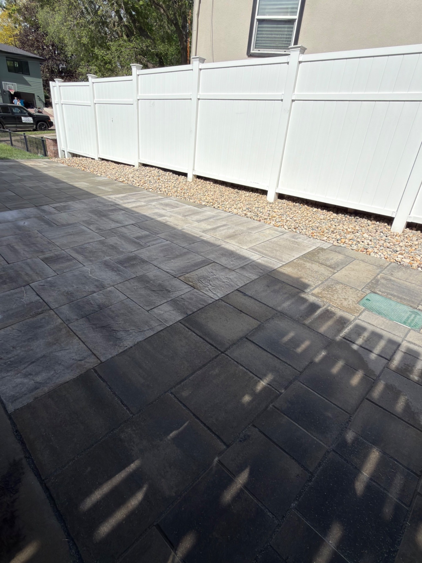 Wide view of completed paver patio with rock drainage strip