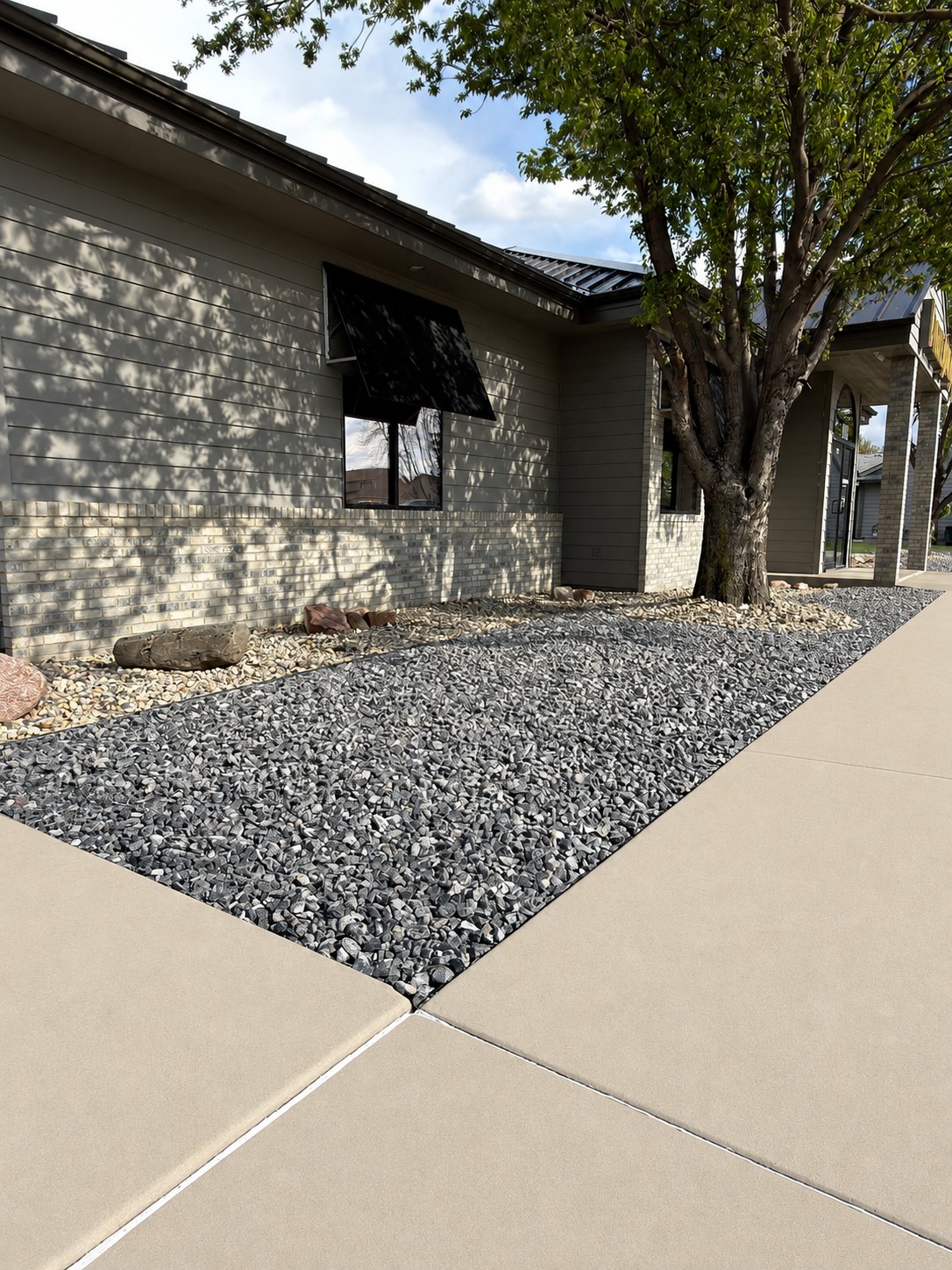 Front of home with fresh gray rock landscaping bed and concrete walkway