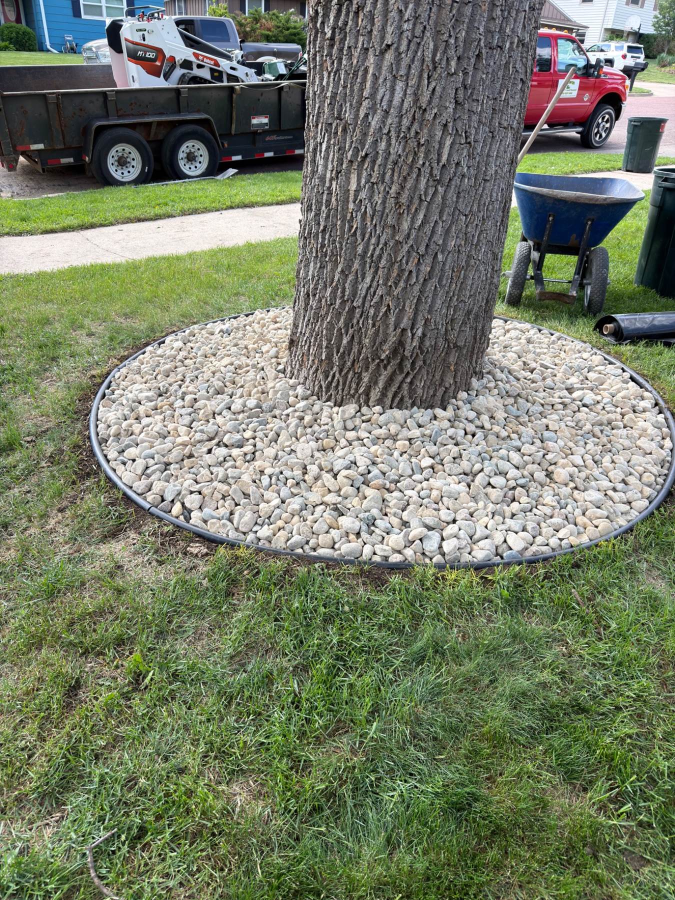 After — finished circular tree ring with steel edging and river rock in the front yard