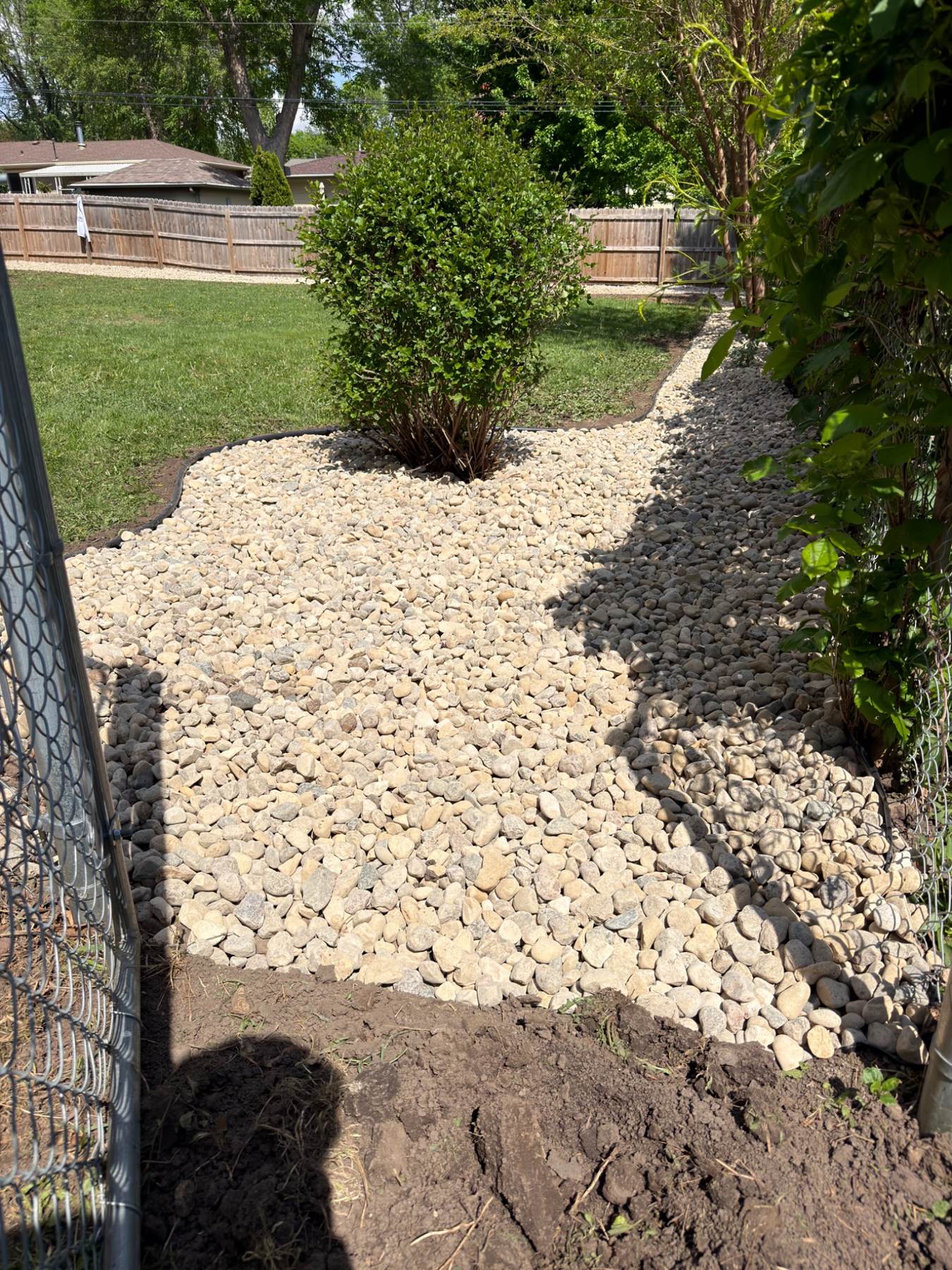 After — two-tone river rock beds with shrub and clean black edging
